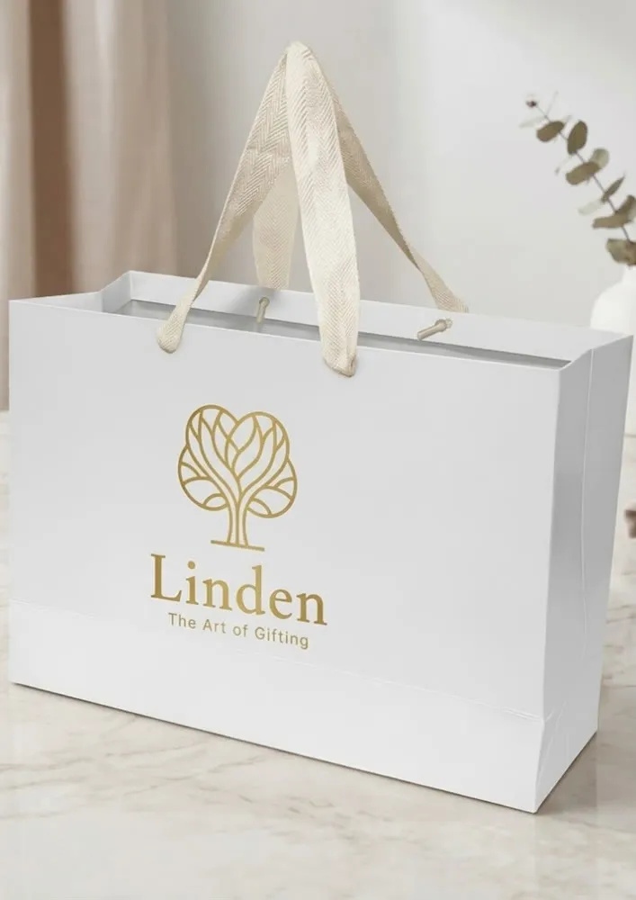Sacola de papel com alça em cetim e a marca impressa na face frontal